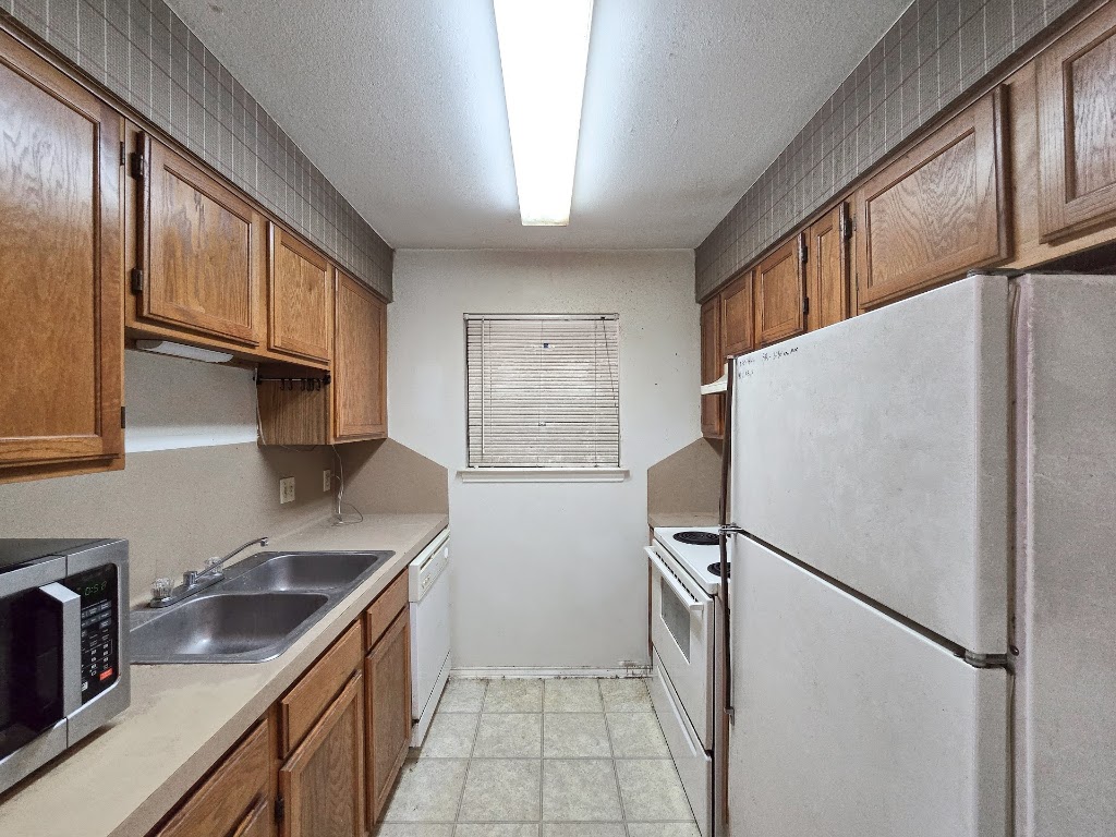 1903 East 20th Street, Unit 202 Austin, TX 78722 - Photo 5 of 8 a kitchen with stainless steel appliances granite countertop a refrigerator a sink dishwasher a stove and a microwave oven with cabinets