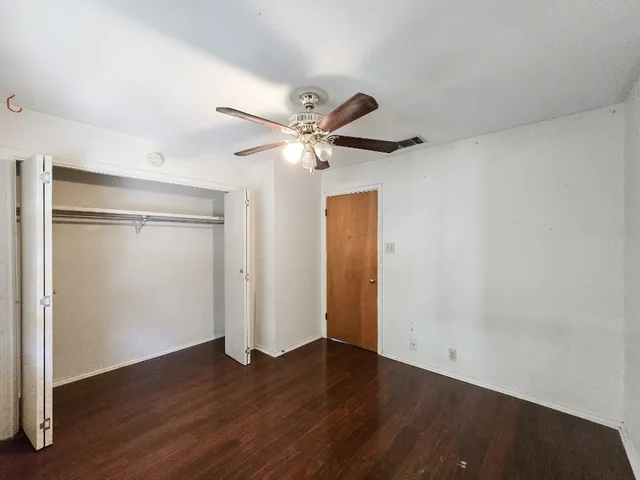 an empty room with wooden floor and a ceiling fan