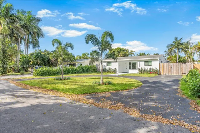 a view of a house with a big yard and palm trees