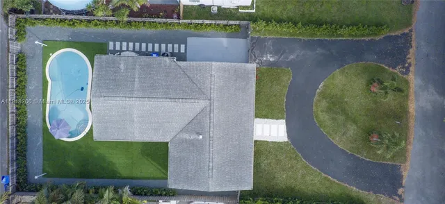an aerial view of a swimming pool with a yard and outdoor seating