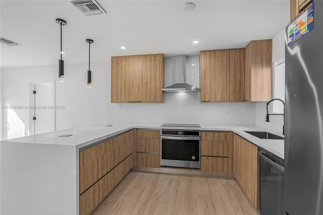a kitchen with stainless steel appliances granite countertop a sink a stove and a refrigerator