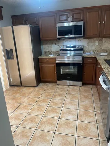a kitchen with granite countertop a stove a refrigerator and a cabinets