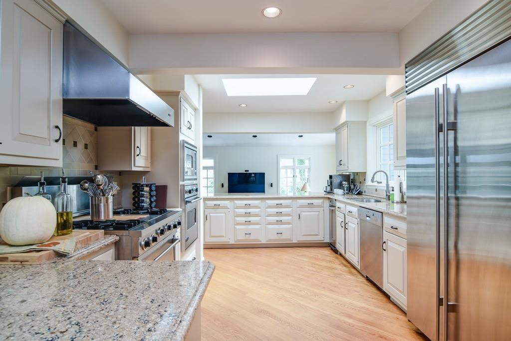 34 Lowell Road Wellesley, MA 02481 - Photo 6 of 14 a large kitchen with stainless steel appliances kitchen island granite countertop a stove a sink dishwasher and a view of living room