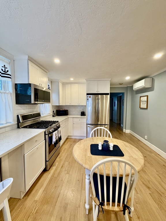176 M Street, Unit 1 Boston, MA 02127 - Photo 4 of 11 a kitchen with stainless steel appliances granite countertop a sink a stove a refrigerator cabinets and a dining table