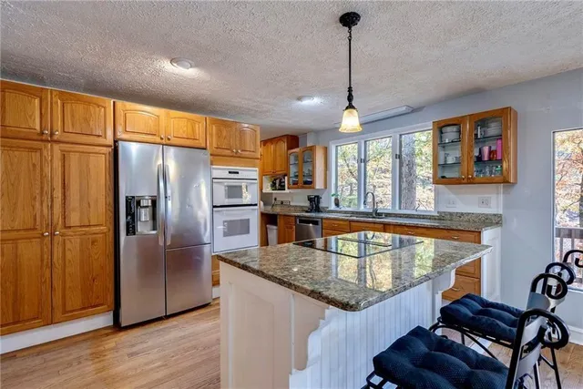 a kitchen with stainless steel appliances granite countertop a refrigerator a stove and a sink with wooden floor