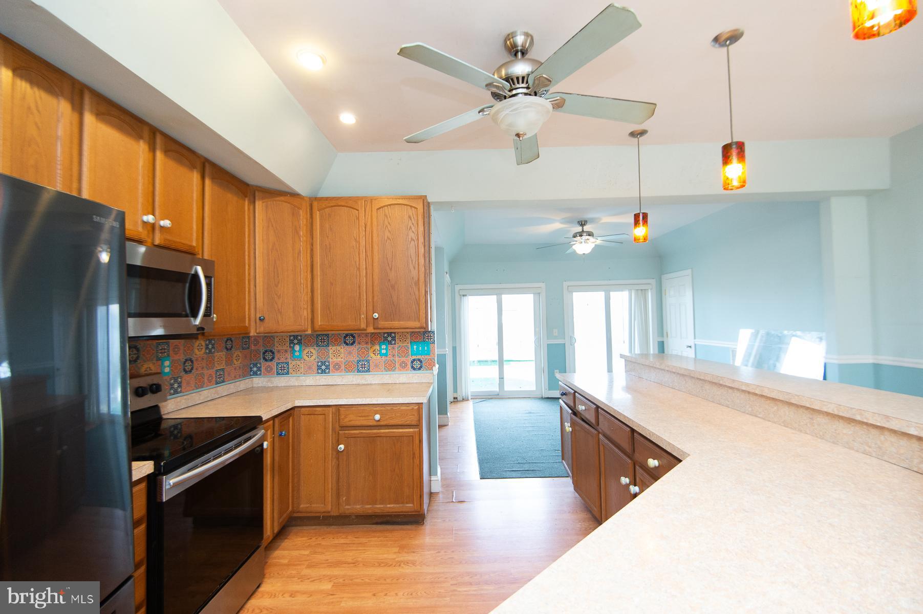 1210 Stone Boundary Road Cambridge, MD 21613 - Photo 18 of 63 a large kitchen with stainless steel appliances kitchen island granite countertop a sink dishwasher stove and refrigerator with wooden floor