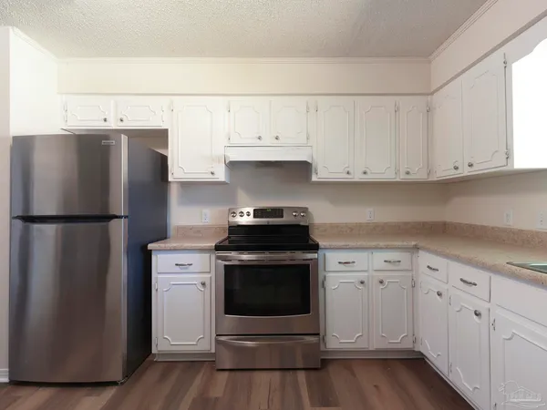 a kitchen with granite countertop white cabinets and stainless steel appliances