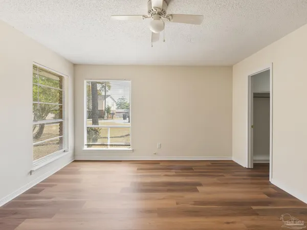 a view of an empty room with a window and wooden floor