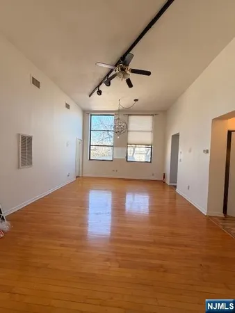 a view of an empty room with chandelier fan and windows