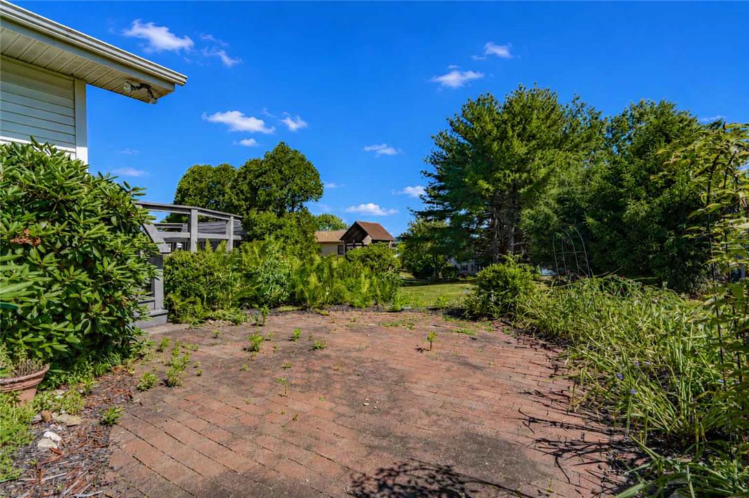 4815 Mill Road Schnecksville, PA 18078 - Photo 44 of 48 A classic brick paver patio extends to a verdant yard with mature trees and landscaping.