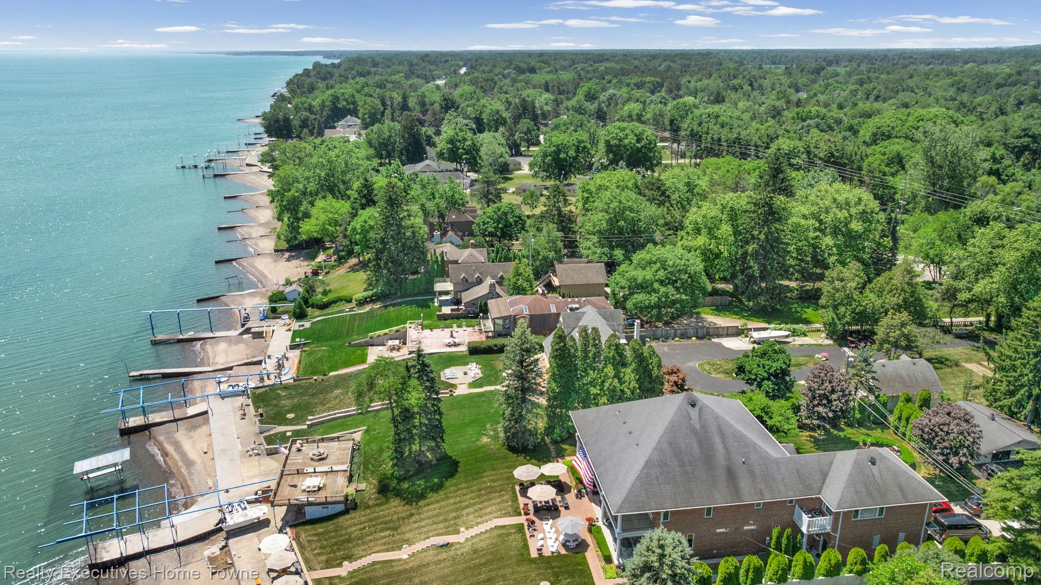 8308 Lakeshore Road Fort Gratiot, MI 48059 - Photo 22 of 79 Expansive waterfront property featuring multiple private docks, tiered landscaping, a large brick residence, and mature tree coverage