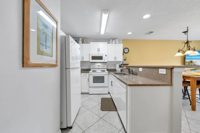 a kitchen with granite countertop white cabinets sink and white appliances