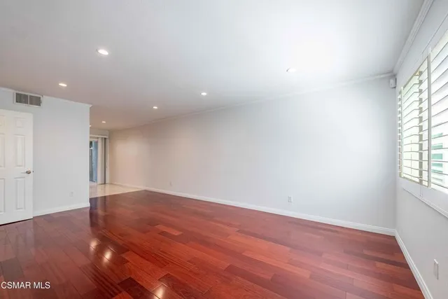 a view of an empty room with wooden floor and stairs
