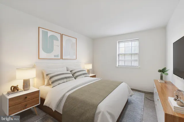 a bedroom with a bed and a lamp on dresser