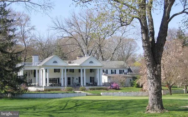 a front view of a house with a garden and trees