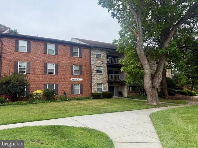 a view of a brick building next to a yard with large trees