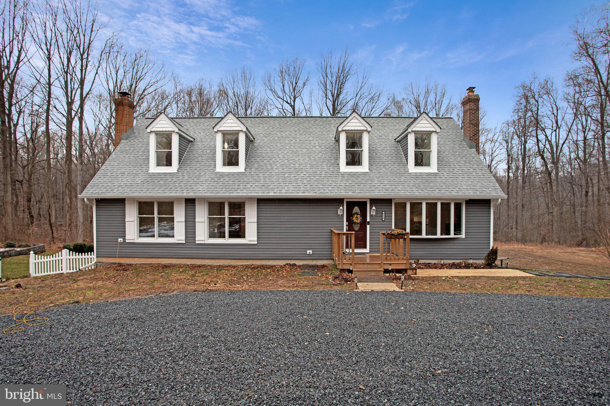 a front view of a house with yard and trees in the background