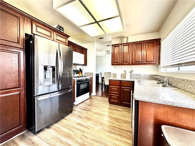a kitchen with granite countertop wooden cabinets a refrigerator and a sink