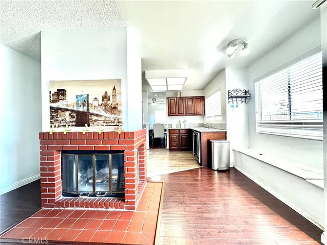 a living room with stainless steel appliances furniture a rug and a kitchen view