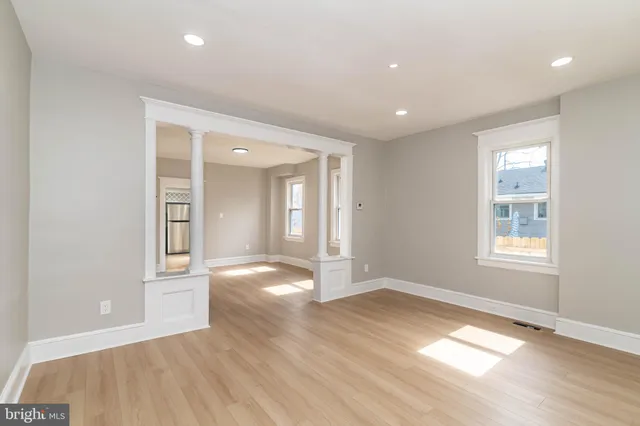 an empty room with wooden floor and windows