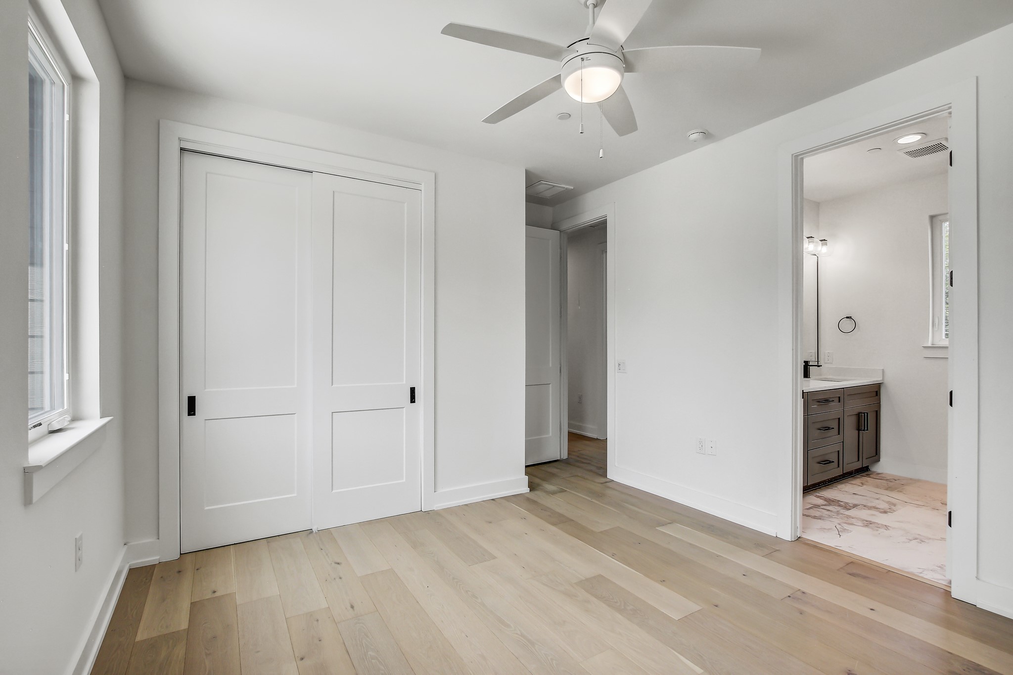 4127 East 12th Street, Unit 3 Austin, TX 78721 - Photo 16 of 29 Unfurnished bedroom with light wood-style floors, a closet, baseboards, and multiple windows