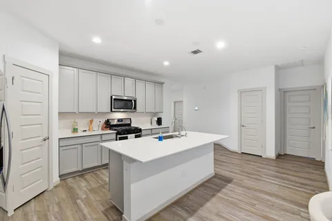 a kitchen with a sink a stove a refrigerator and white cabinets