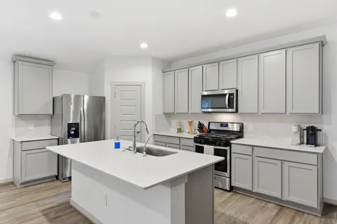 a kitchen with stainless steel appliances granite countertop white cabinets and a stove top oven