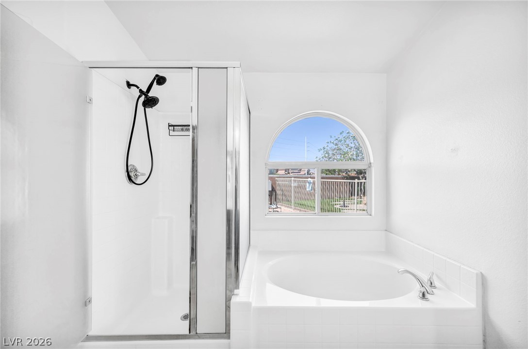 6405 North Raptor Court North Las Vegas, NV 89084 - Photo 35 of 66 A deep soaking tub sits beneath an elegant arched window, complementing the adjacent stand-up shower.