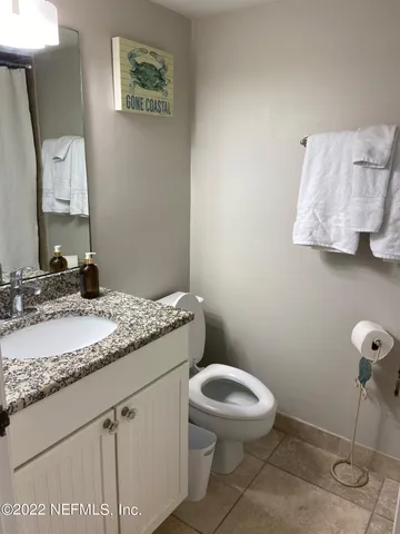 a bathroom with a granite countertop toilet sink and mirror