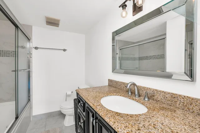 a bathroom with a granite countertop sink toilet and shower