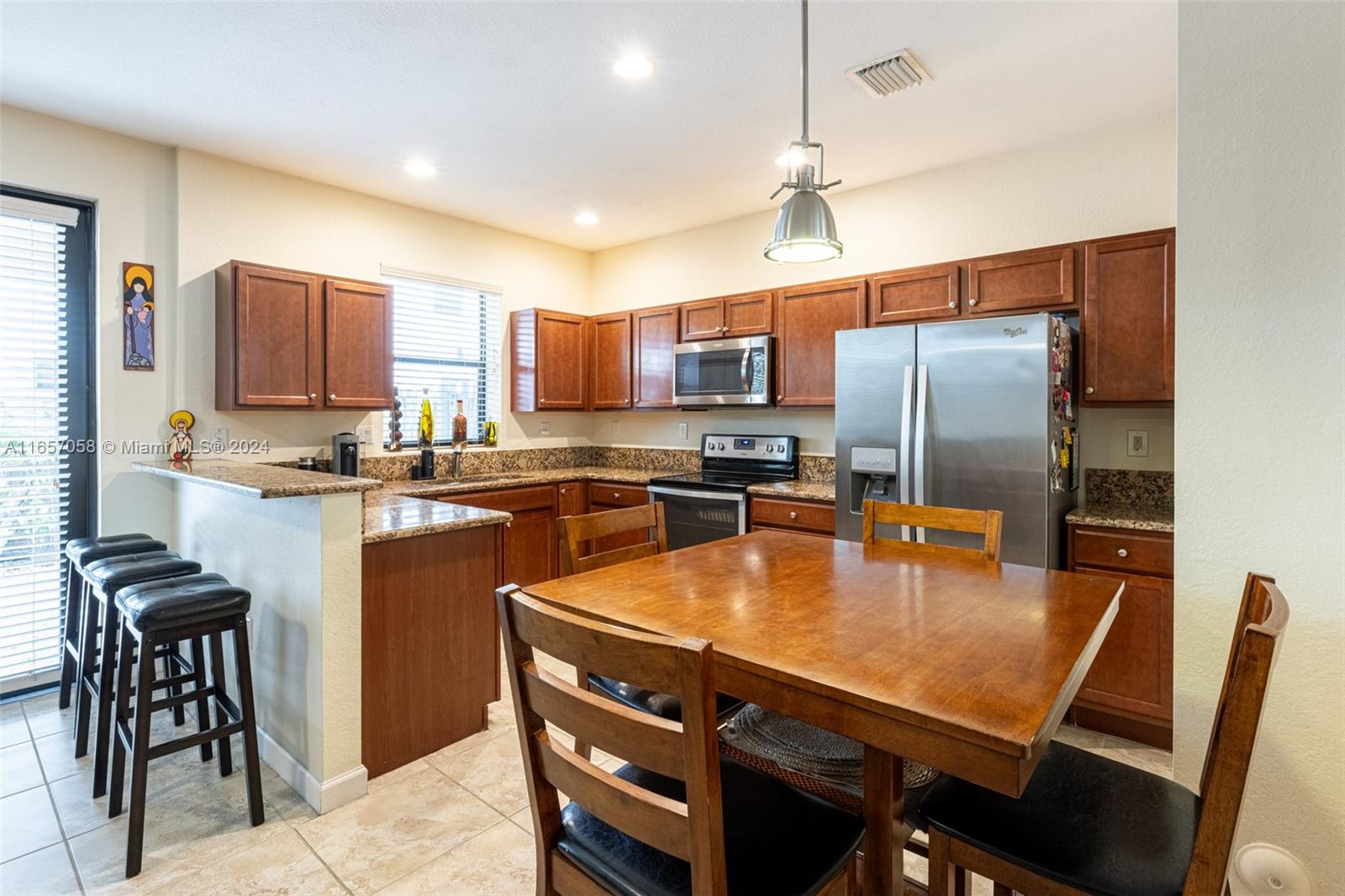 23578 Southwest 113th Path Homestead, FL 33032 - Photo 17 of 59 a kitchen with stainless steel appliances granite countertop a refrigerator a stove a sink a dining table and chairs