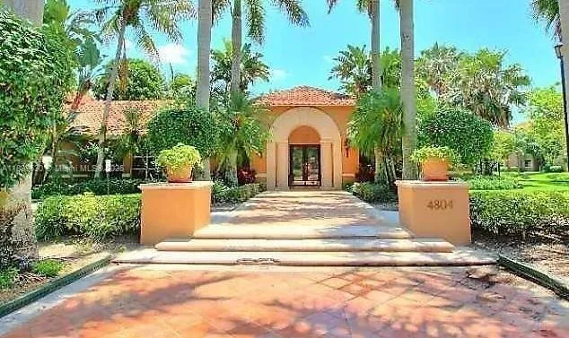 a view of a white house with a yard and potted plants