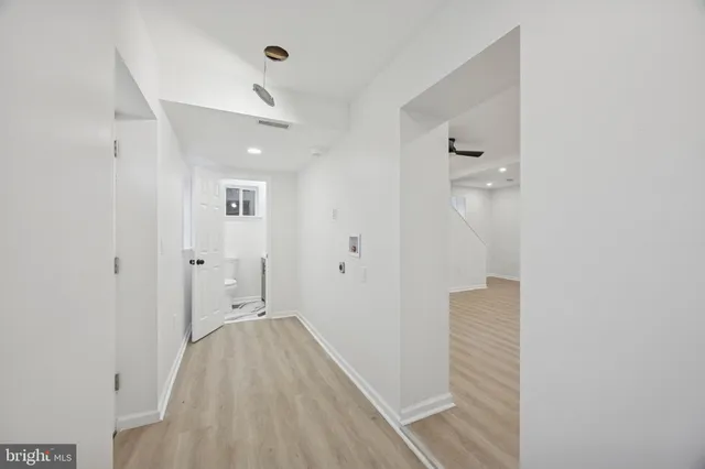 a view of a hallway with wooden floor and a bathroom