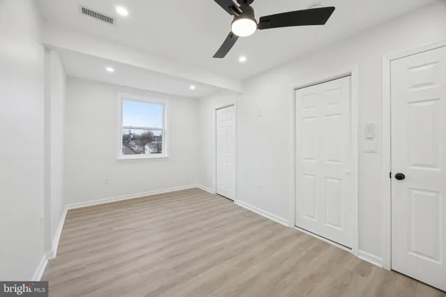 an empty room with wooden floor ceiling fan and windows