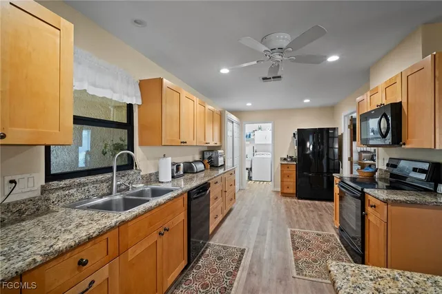 a large kitchen with stainless steel appliances granite countertop a sink refrigerator and cabinets