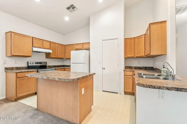 a view of an empty room and a kitchen