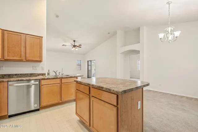 an empty room with a chandelier fan and windows