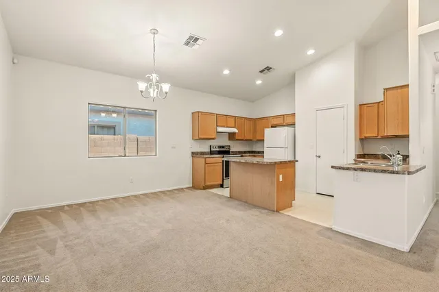 a kitchen with stainless steel appliances granite countertop a stove a refrigerator a sink dishwasher and white cabinets with wooden floor