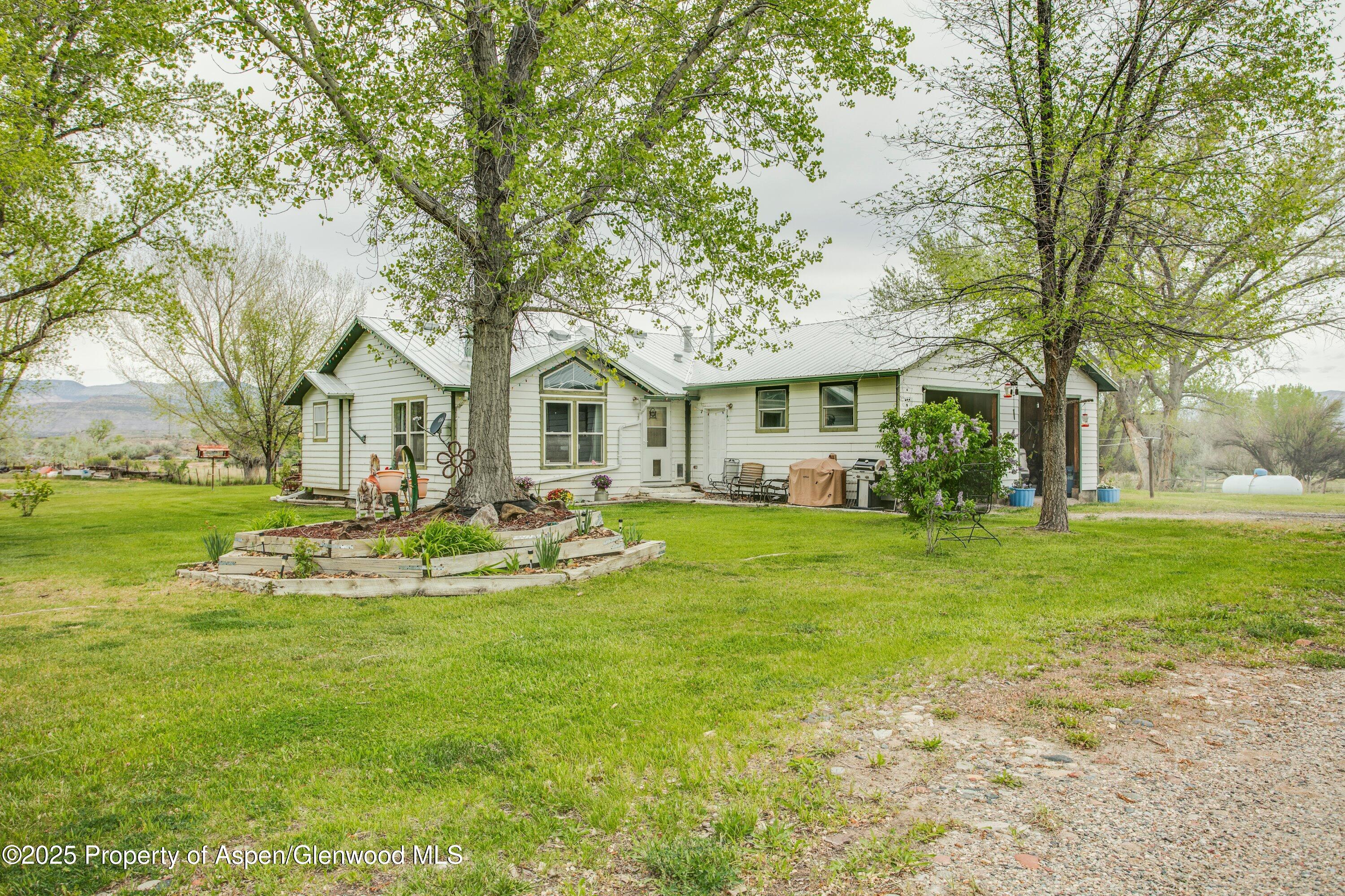 70 Frontage Road De Beque, CO 81630 - Photo 15 of 26 a view of a white house with a big yard and large trees