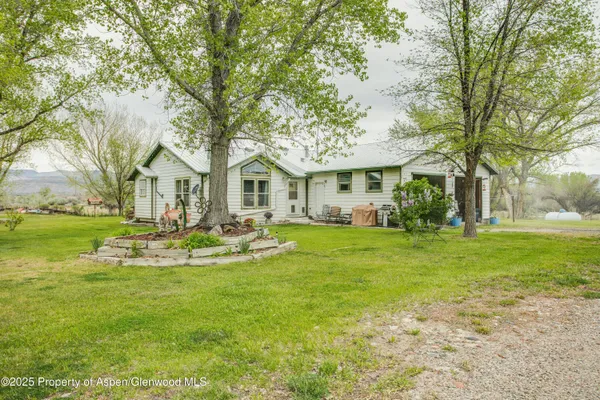 a view of a white house with a big yard and large trees