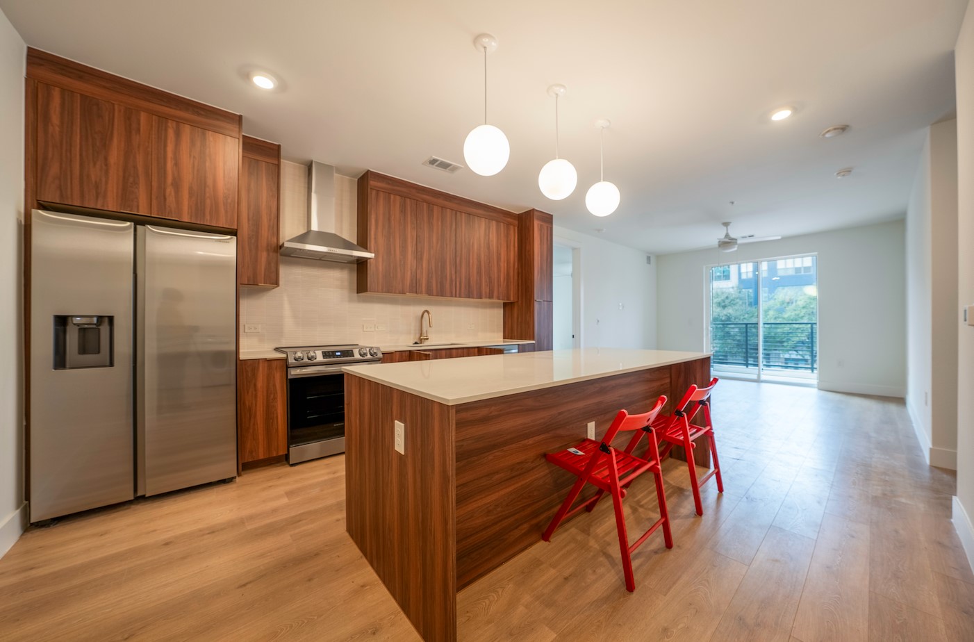 1701 Simond Avenue, Unit 212 Austin, TX 78723 - Photo 2 of 28 Kitchen with stainless steel appliances, hanging light fixtures, wood finish cabinetry, modern cabinets, and a kitchen island
