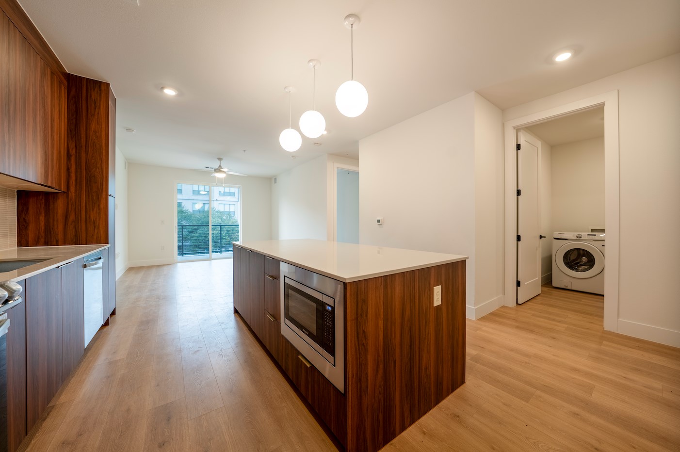 1701 Simond Avenue, Unit 212 Austin, TX 78723 - Photo 6 of 28 Kitchen featuring modern cabinets, hanging light fixtures, washer / dryer, a kitchen island, and light wood-style flooring