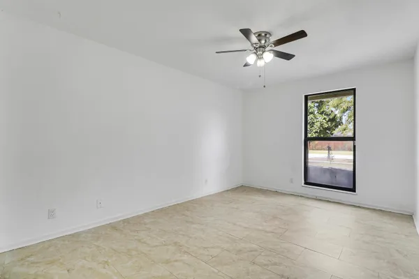 an empty room with windows and ceiling fan