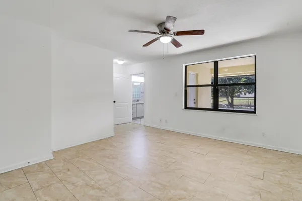 an empty room with windows and ceiling fan