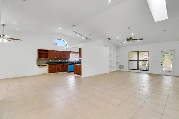 an empty room with windows and kitchen view