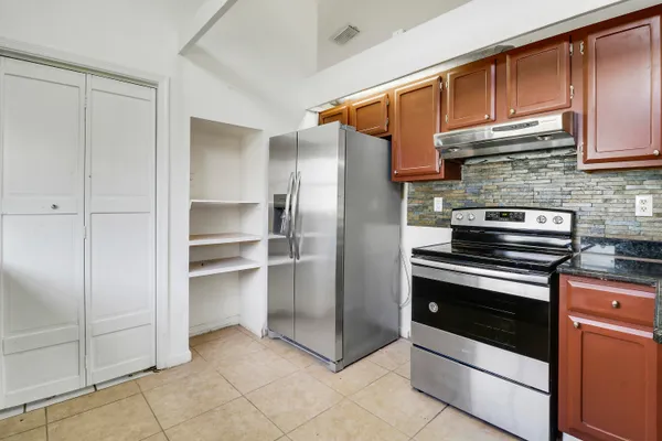 a kitchen with granite countertop a refrigerator and a stove top oven