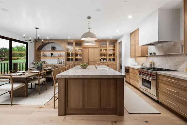 a kitchen with a stove a sink dishwasher and a dining table with garden view