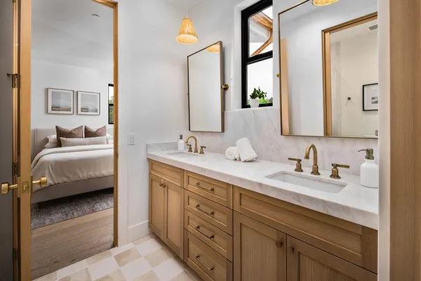 a en suite bathroom with double vanity a mirror and a bathtub