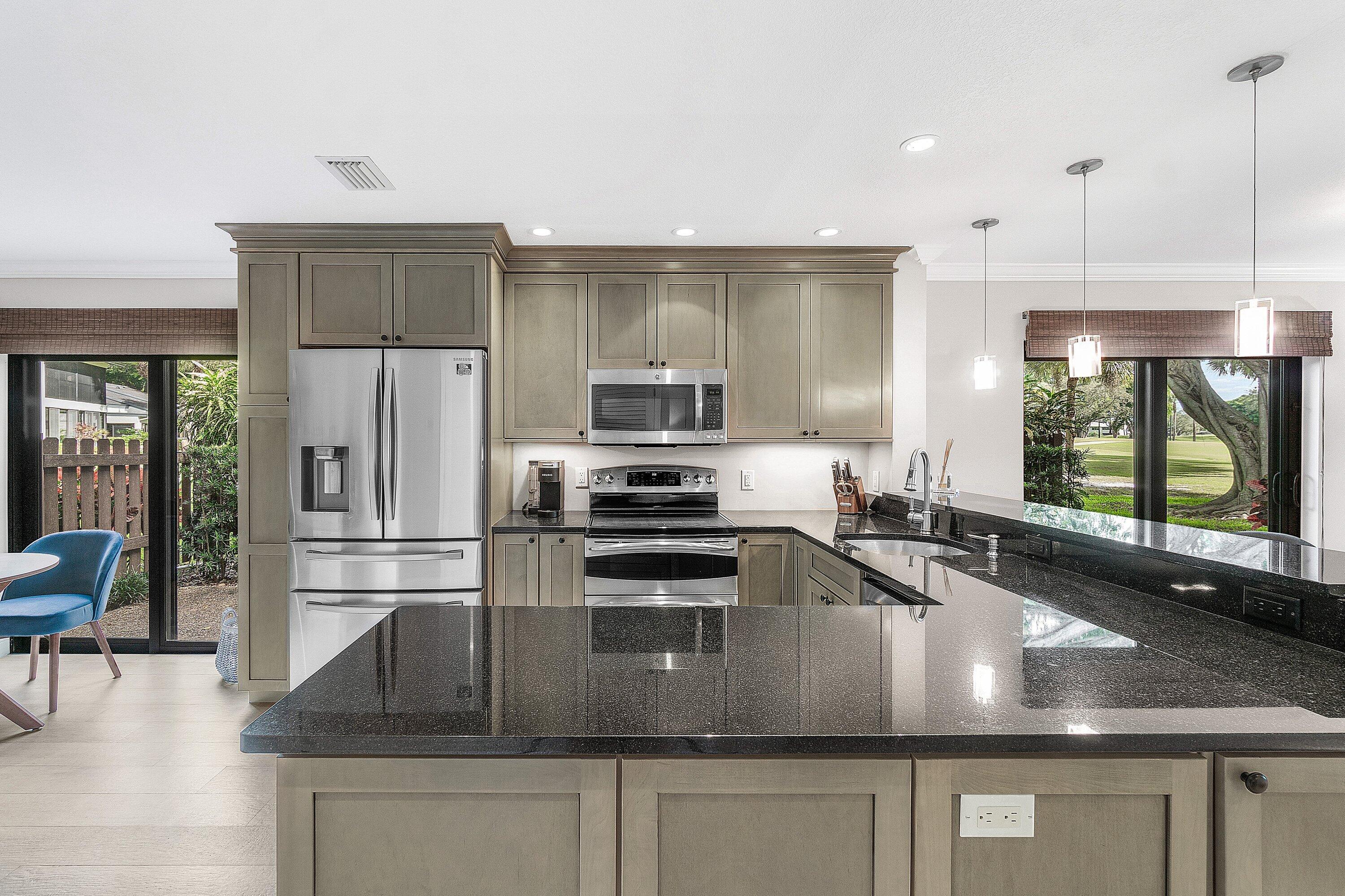 38 Southport Lane, Unit A Boynton Beach, FL 33436 - Photo 10 of 65 a kitchen with stainless steel appliances granite countertop a sink a stove and a refrigerator