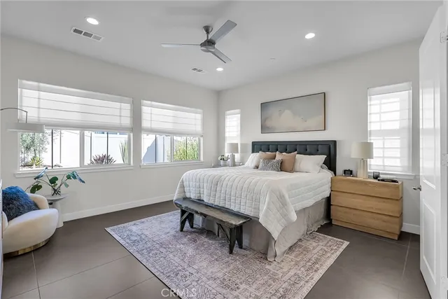 a bedroom with a large bed couch and windows